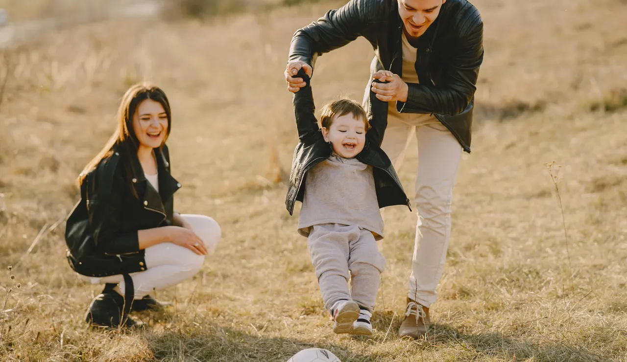 Una madre y un padre juegan a la pelota con su hijo 