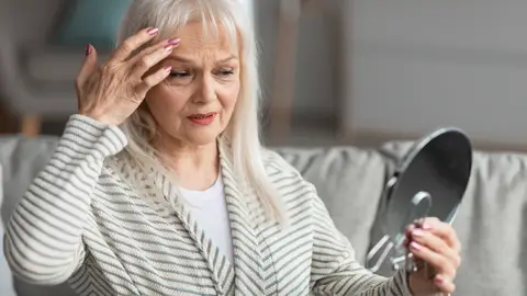 Mujer contemplando sus signos de envejecimiento