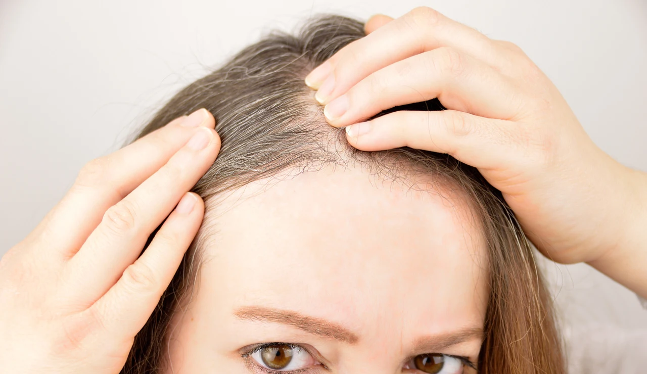 Una mujer observa la raíz de su cabello.