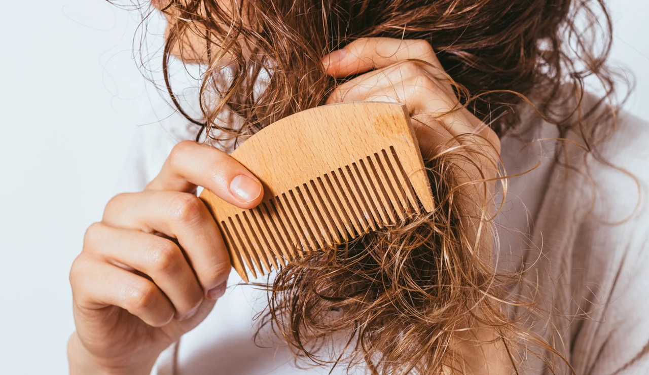 Mujer con pelo encrespado intentando peinarse