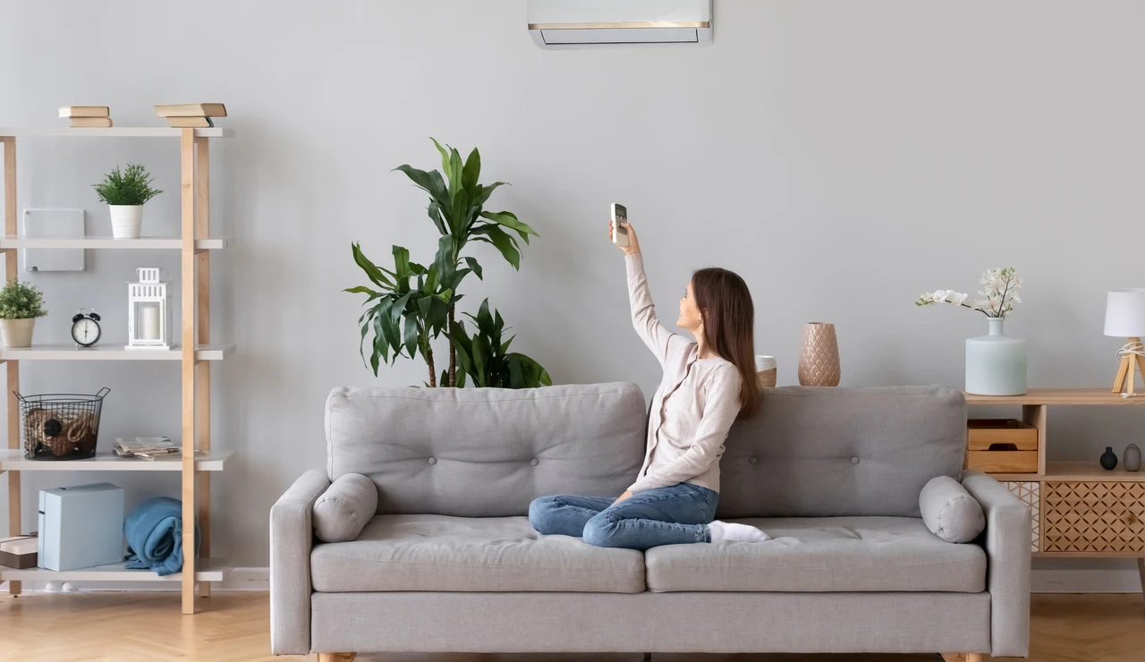 Una mujer poniendo el aire acondicionado en su salón