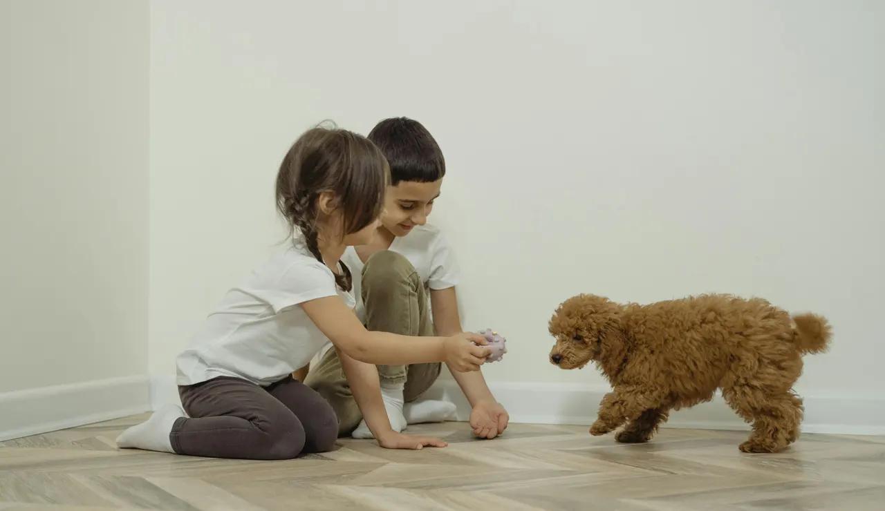 Una niña y un niño con un perro en casa.