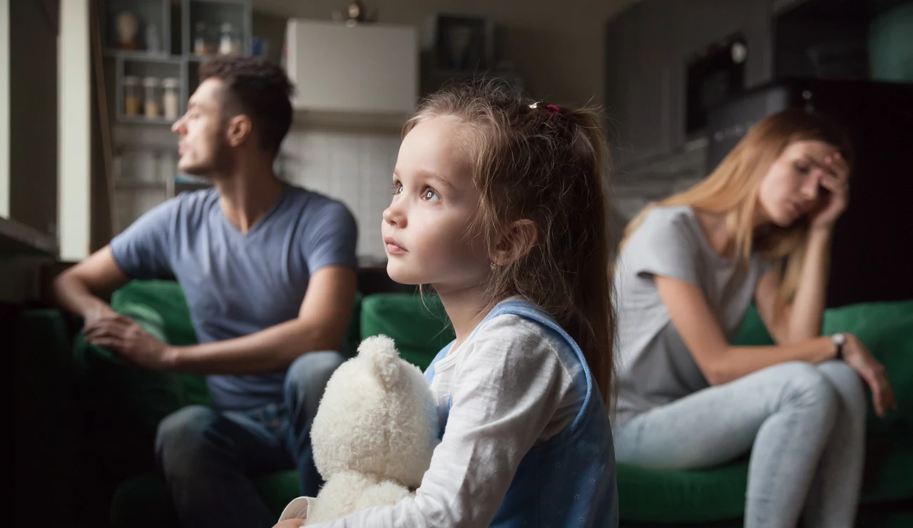 Una niña pequeña y los padres divorciados detrás