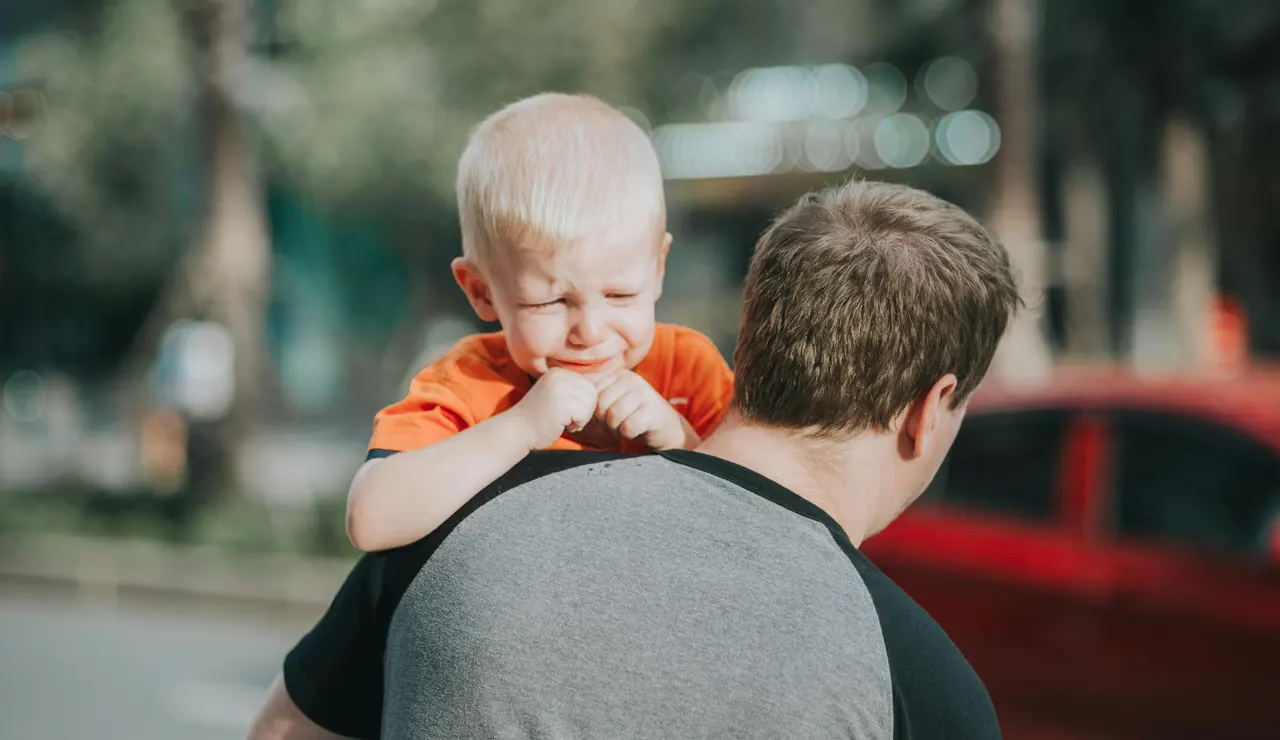 Un niño llora en brazos de su padre