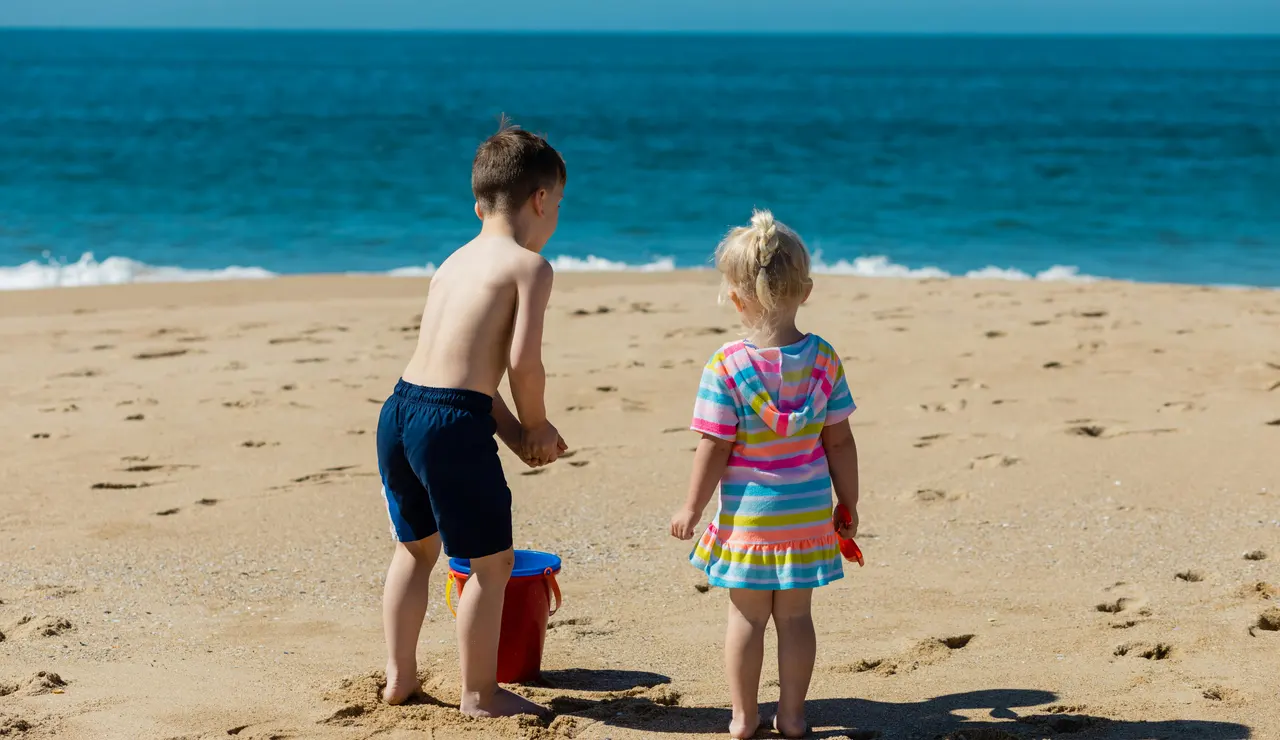 Un niño y una niña juegan en la arena de la playa