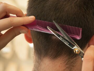 Un peluquero corta el pelo a un joven