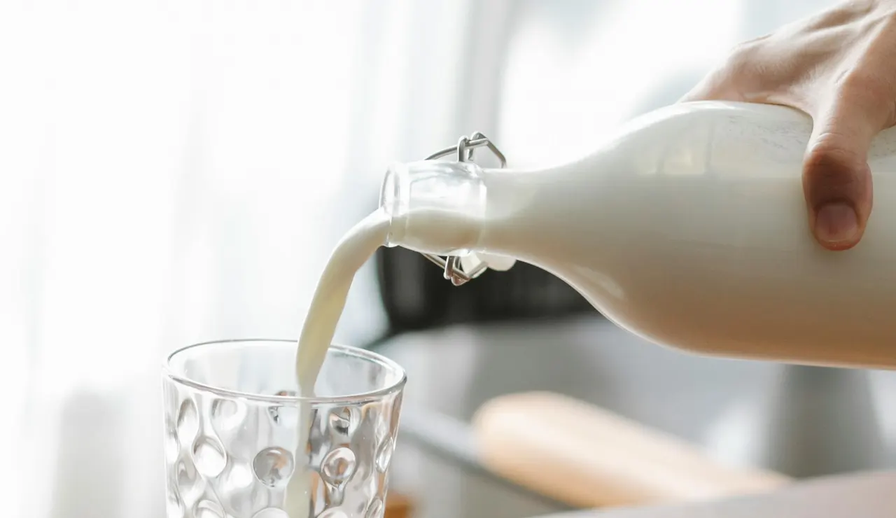 Una persona sirviendo un vaso de leche